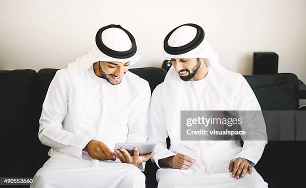 arab friends browsing social media using digital tablet - middle east friends stock pictures, royalty-free photos & images