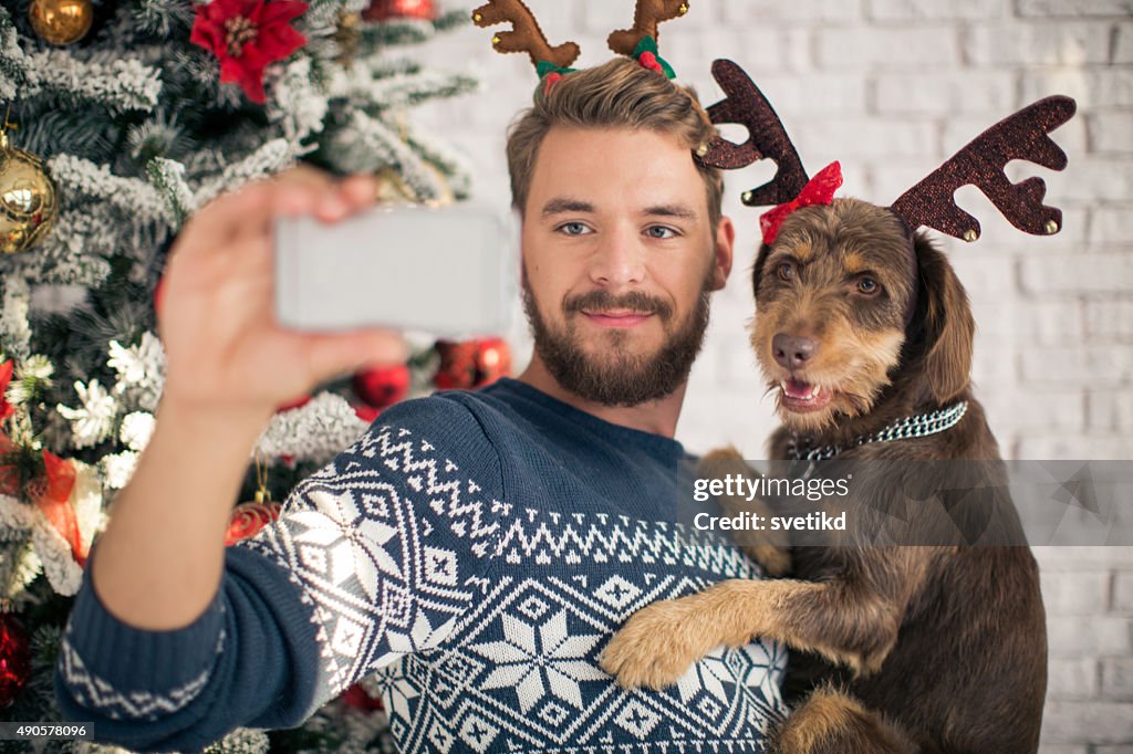 Man with his dog taking selfies for christmas.