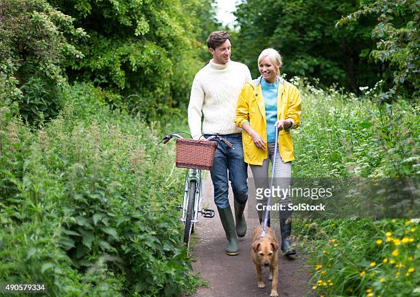 pleasant company while walking the dog - couple walking in park stock pictures, royalty-free photos & images