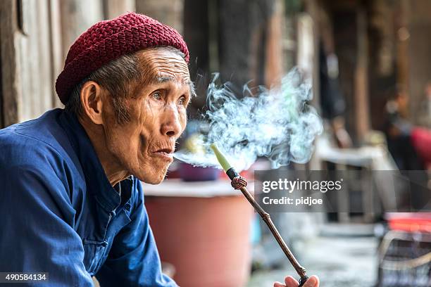 cinese vecchio uomo anziano fumare pipe, contemplativa - pipa prodotto a base di tabacco foto e immagini stock