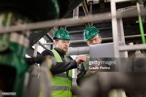manual workers discussing while using laptop at factory - concentration stock pictures, royalty-free photos & images