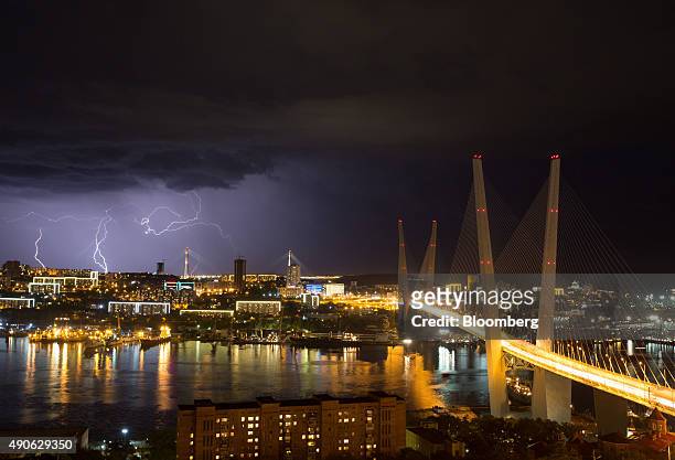 Lightning strikes the city skyline at night beyond the Golden bridge on Golden Horn Bay in Vladivostok, Russia, on Sunday, Sept. 27, 2015. "It is...