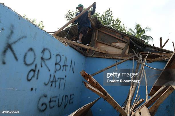 Graffiti referencing the Jatigede dam covers the wall of a vacated house as a worker removes materials in Pada Jaya village in Sumedang Regency, West...