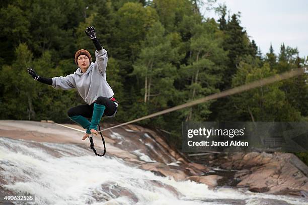 female slackliner standing up on a slackline that spans a river - slacklining stock pictures, royalty-free photos & images