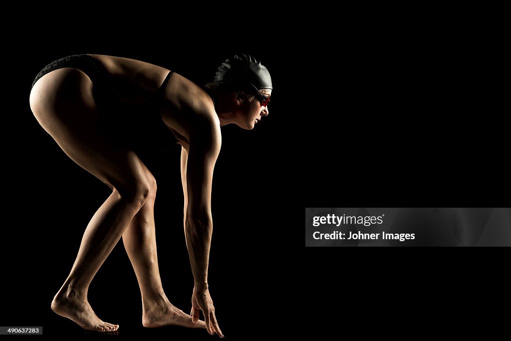 Mid adult woman in swimwear preparing for jump