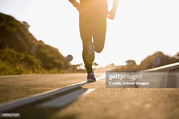 runner running on road, low section - running legs ストックフォトと画像