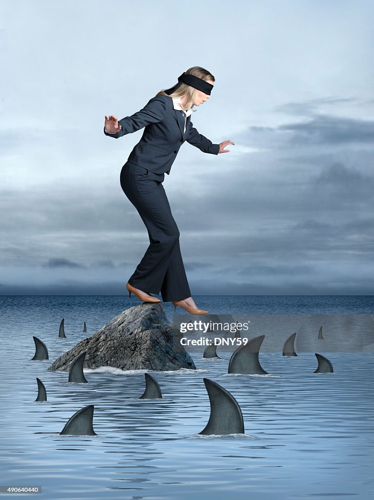 Blindfolded Businesswoman Surrounded by Sharks