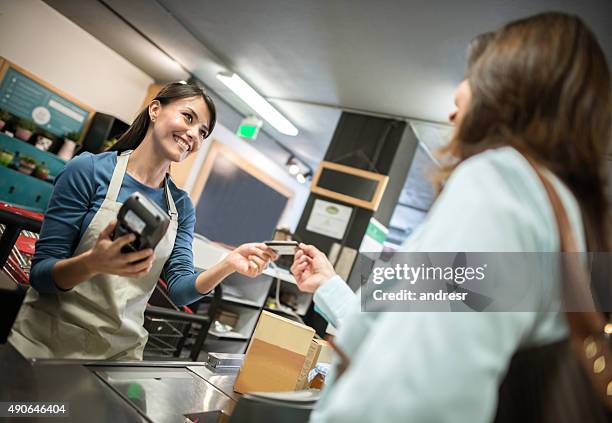 cashier at the supermarket getting a card payment - card payments stock pictures, royalty-free photos & images