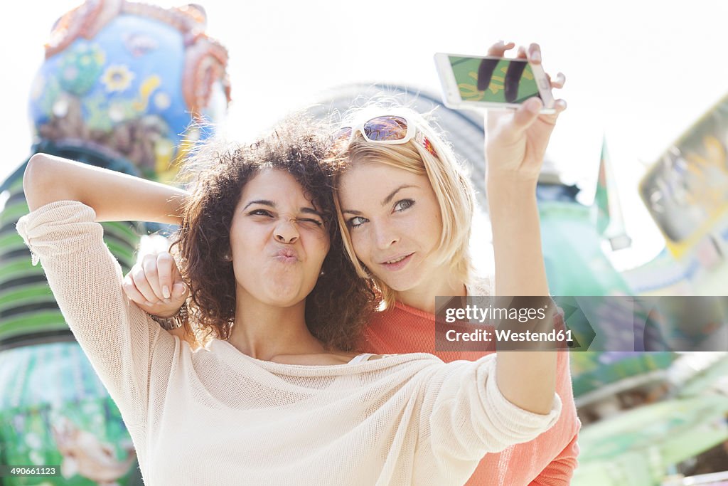 Germany, Herne, Two young women at the fairground photographing self