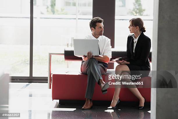 businessman and businesswoman talking in office lobby - two people talking face to face stock-fotos und bilder
