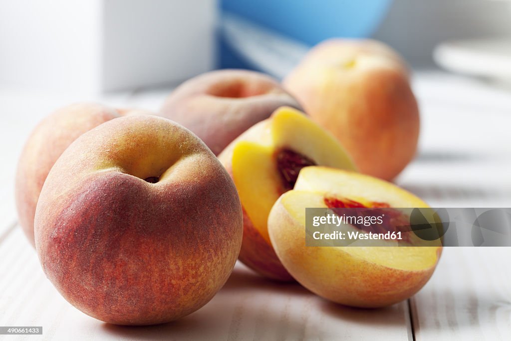 Whole and sliced peaches (Prunus persica) on white wooden table