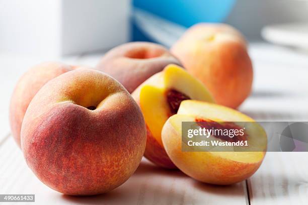 whole and sliced peaches (prunus persica) on white wooden table - half complete stock pictures, royalty-free photos & images