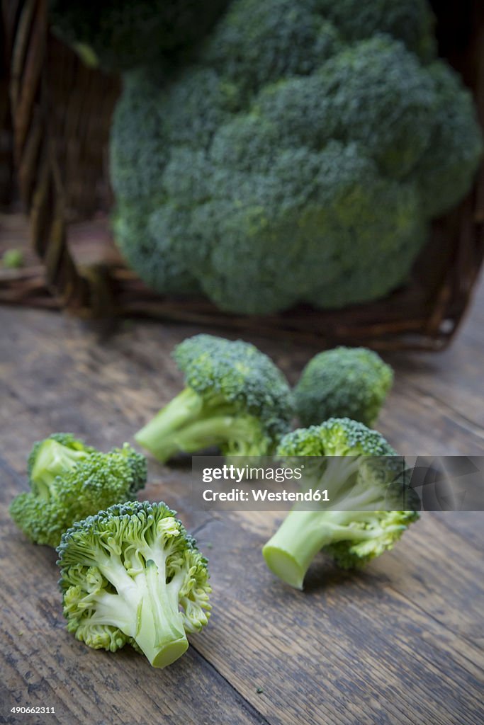 Broccoli florets and broccoli (Brassica oleracea var. italica) on wooden table