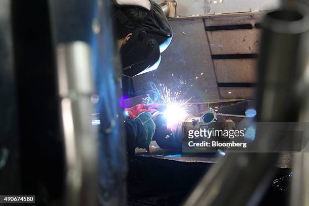 An employee welds parts on to a automobile catalytic converter emission control device at BM Catalysts in Mansfield, U.K., on Wednesday, Sept. 30,...