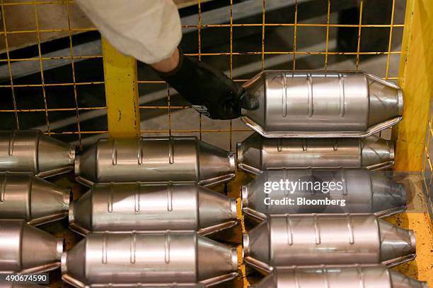 An employee places a automobile catalytic converter emission control device into a trolley at BM Catalysts in Mansfield, U.K., on Wednesday, Sept....