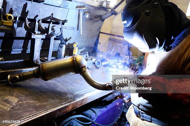 An employee welds parts on to a automobile catalytic converter emission control device at BM Catalysts in Mansfield, U.K., on Wednesday, Sept. 30,...