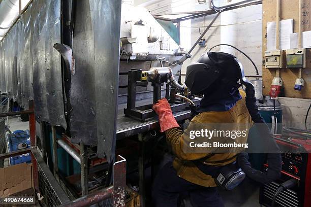 An employee welds parts on to an automobile catalytic converter emission control device at BM Catalysts in Mansfield, U.K., on Wednesday, Sept. 30,...