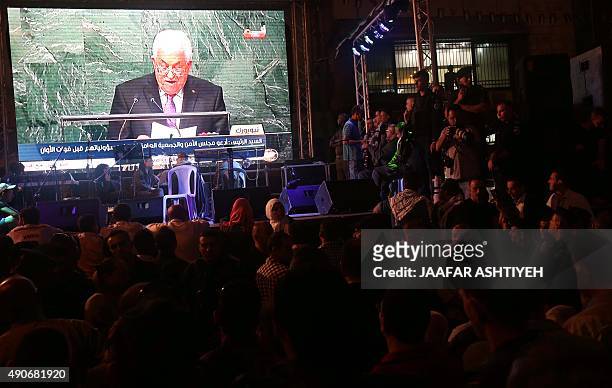 Palestinians watch the speech of their president Mahmud Abbas on a giant screen as he addresses the world at the United Nations headquarters in New...