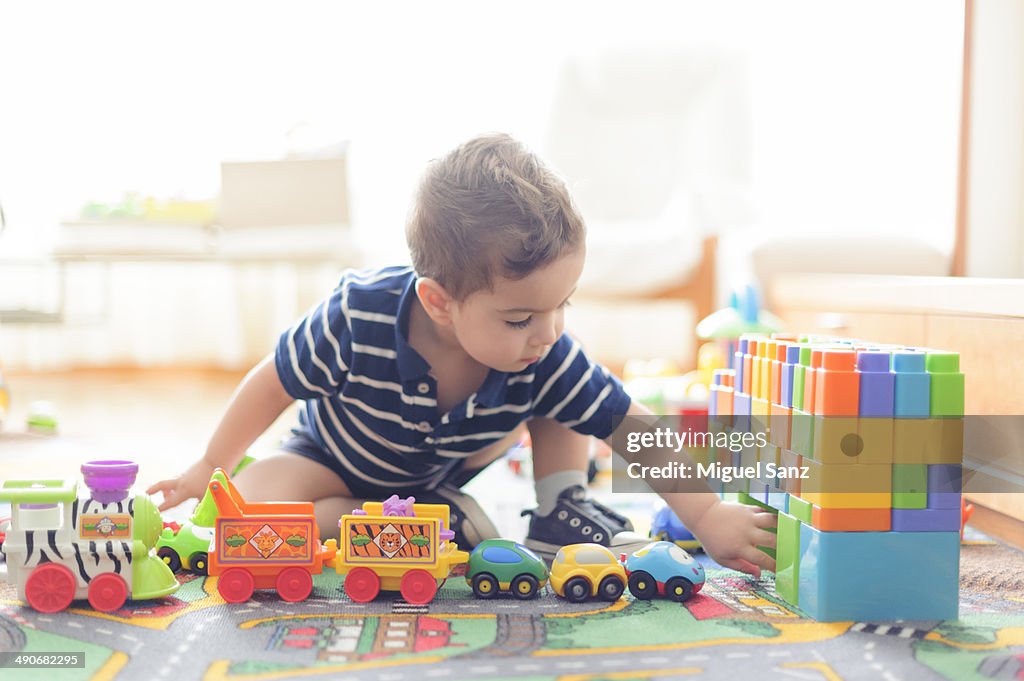 Kid playing with a train and small cars at home