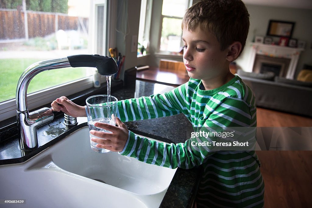 Boy Turning Off Tap After Getting Water