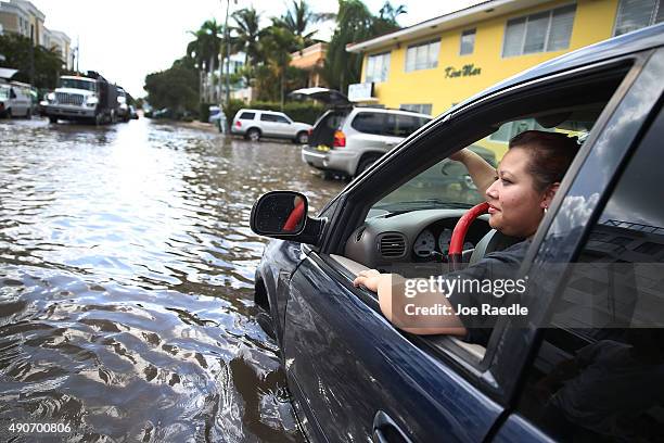 Sandy Garcia sits in her vehicle that was stuck in a flooded street caused by the combination of the lunar orbit which caused seasonal high tides and...