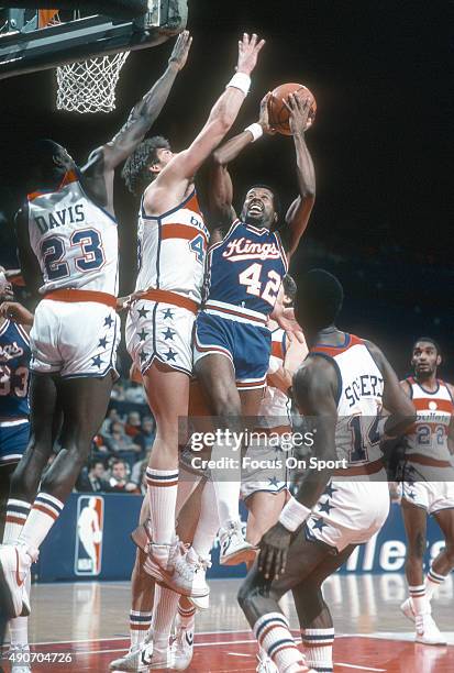Mike Woodson of the Kansas City Kings looks to get his shot off over Jeff Ruland and Charles Davis of the Washington Bullets during an NBA basketball...