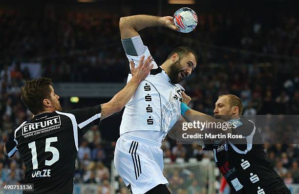 Joan Canellas of Kiel challenges for the ball with Alexander Oelze and Jan Artmann of Bergischer HC during the DKB HBL Bundesliga match between THW...