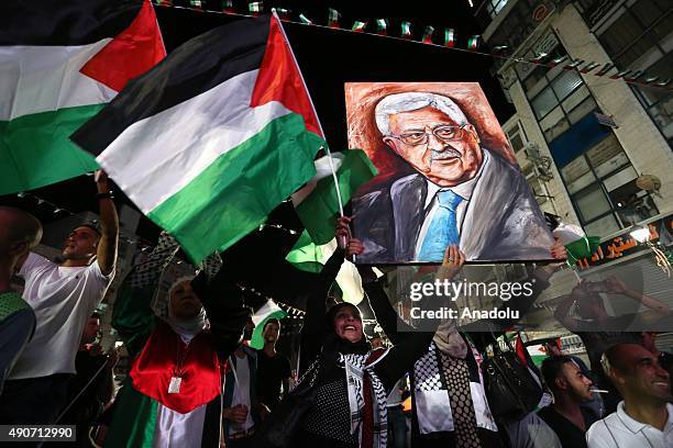 Palestinians wave their national flags as they watch a live-screening of president Mahmoud Abbas' speech followed by the raising of the Palestinian...