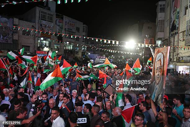 Palestinians wave their national flags as they watch a live-screening of president Mahmoud Abbas' speech followed by the raising of the Palestinian...