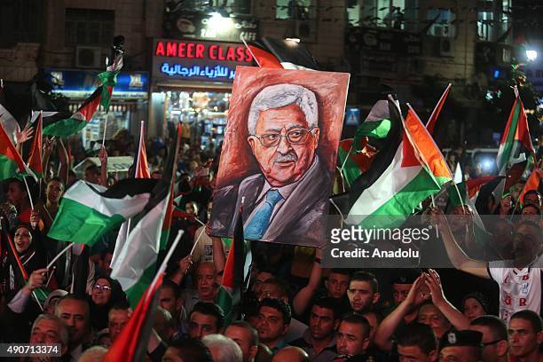 Palestinians wave their national flags as they watch a live-screening of president Mahmoud Abbas' speech followed by the raising of the Palestinian...