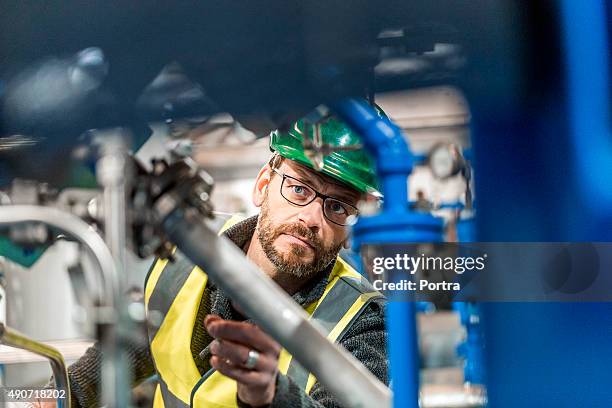 manufacturing worker analysing machines at factory - pipe stockfoto's en -beelden