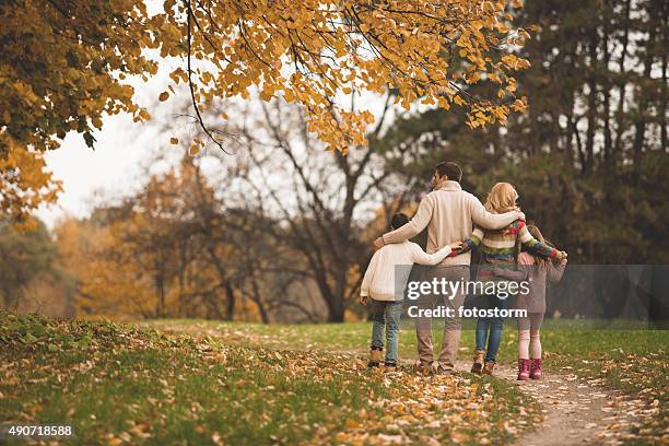 family walking in the park - drops back stock pictures, royalty-free photos & images