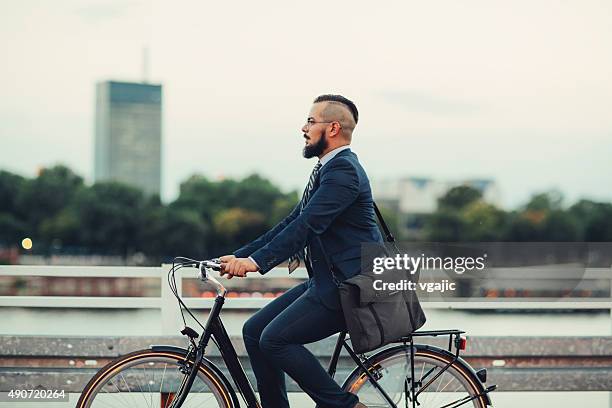 businessman ride bicycle from work late. - laptop bag stock pictures, royalty-free photos & images