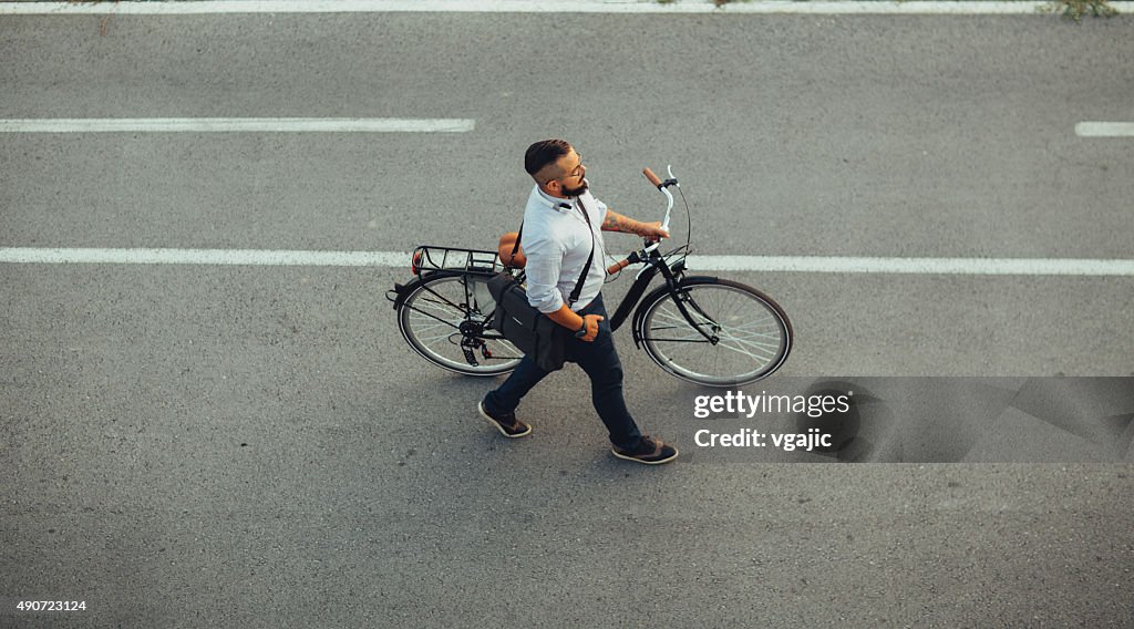 Uomo d'affari spingendo bicicletta e andare a casa a tarda notte.