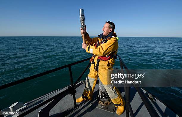 In this handout image provided by Glasgow 2014 Ltd, Jason Norman, Skipper of the St Peter Port Lifeboat 'Spirit of Guernsey', holds the Queen's Baton...