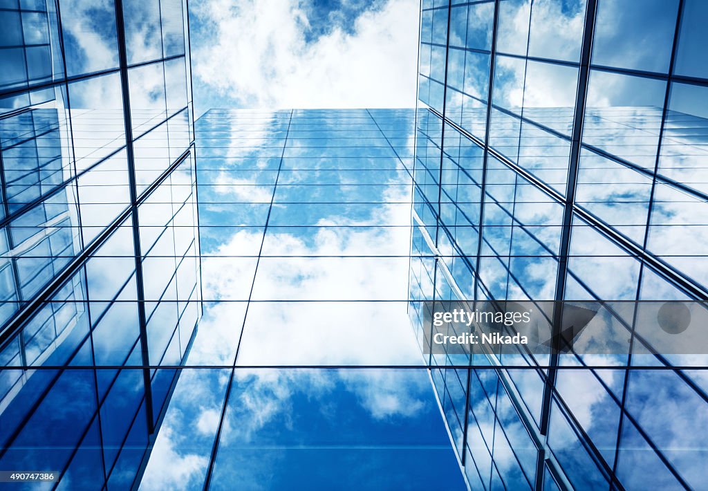 Blauer Himmel und Wolken sich in moderner Glas-Architektur