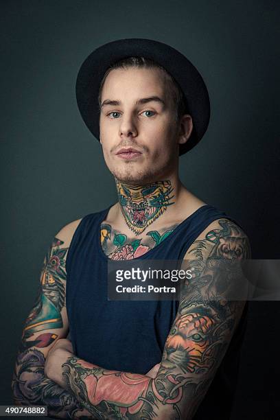 young tattooed man standing arms crossed - tattoo arm stockfoto's en -beelden