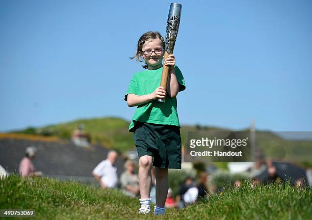 In this handout image provided by Glasgow 2014 Ltd, Mia Carpenter, aged seven, carries the Commonwealth Games Baton as it makes it's way around the...