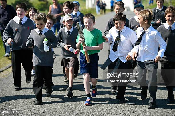 In this handout image provided by Glasgow 2014 Ltd, Karl Huddart, aged 10, carries the Commonwealth Games Baton as it makes it's way around the...