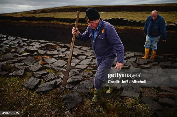 Dan Smith and Donald Campbell, extract peat from a moor near the village of Cross on May 14, 2014 in Lewis, Scotland. The tradition of peat cutting...
