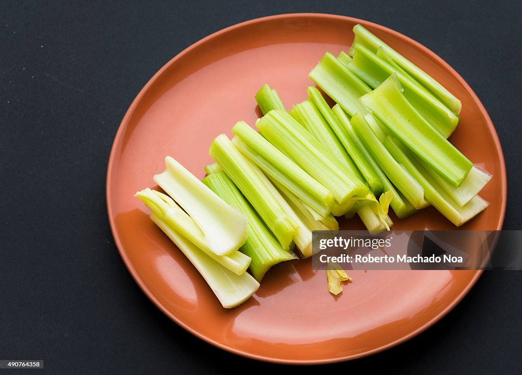 Chopped celery Sticks placed in brown plate against a black...