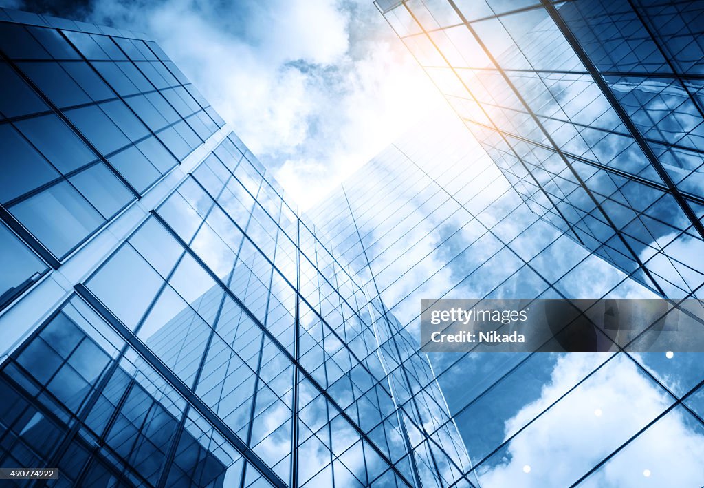 View of a contemporary glass skyscraper reflecting the blue sky