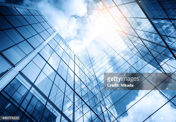 view of a contemporary glass skyscraper reflecting the blue sky - below stock pictures, royalty-free photos & images