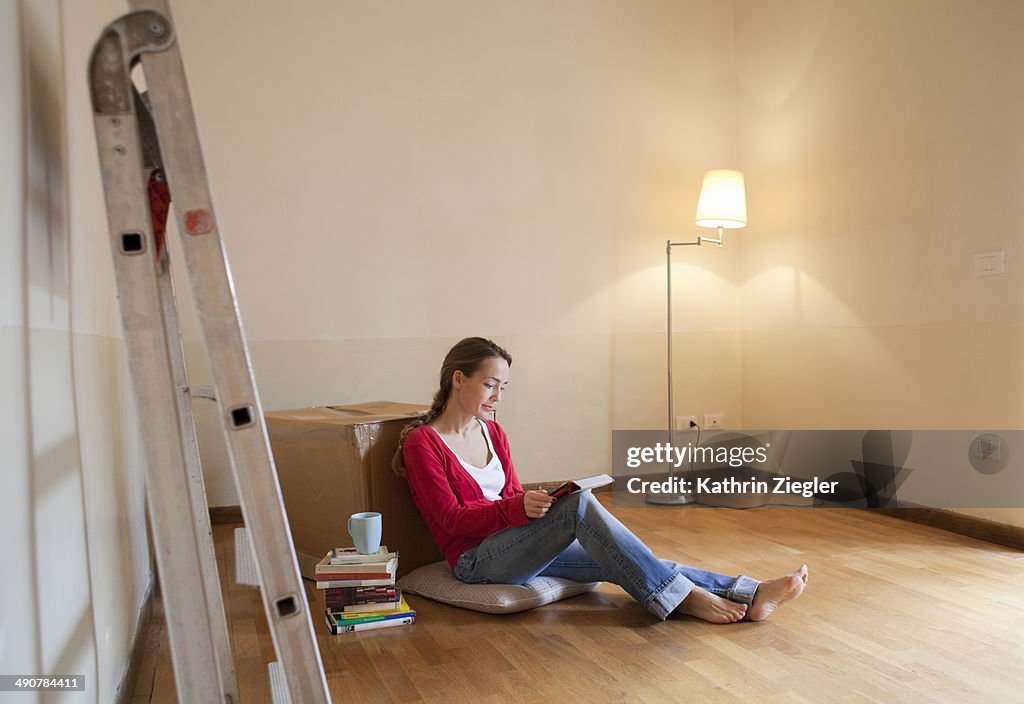 Woman sitting on floor of her new, empty apartment