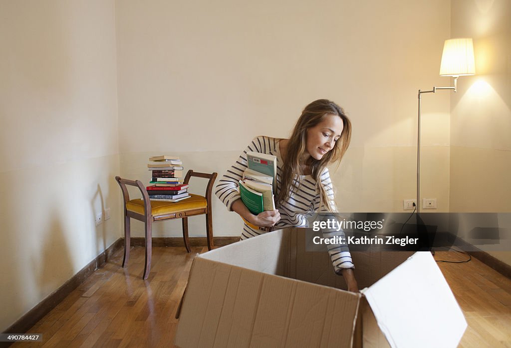 Woman unpacking box with books in her new house