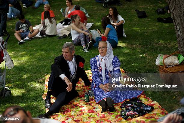 Couple dressed as 'Chulapos' sit on the grass during the San Isidro festivities at Pradera de San Isidro park on May 15, 2014 in Madrid, Spain....