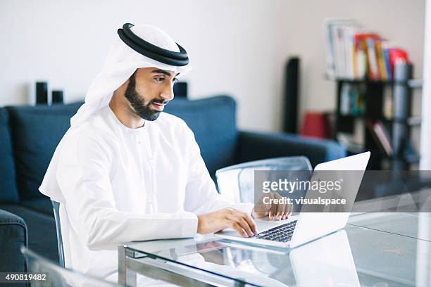 content arab man using laptop at home - west asia stock pictures, royalty-free photos & images