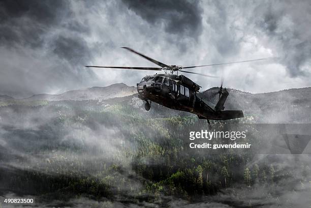 army helicopter flies over foggy mountains - military helicopter stock pictures, royalty-free photos & images