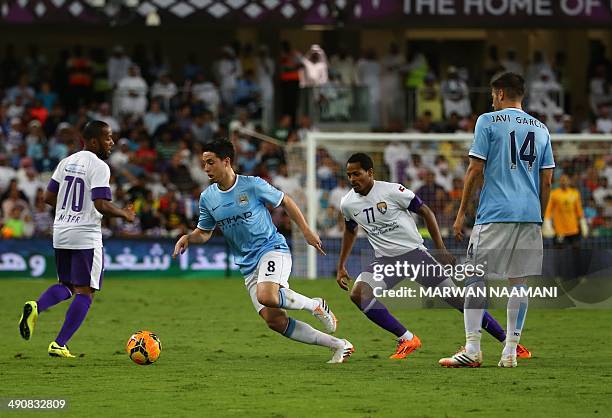 Samir Nasri of newly-crowned English Premier League champions Manchester City football team dribbles the ball between UAE's Al-Ain players Mohamed...