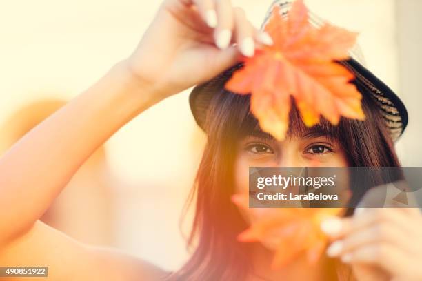 young woman holding autumn leafs in hands - young leafs stockfoto's en -beelden